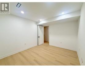 A room with a wooden floor and a door leading to another room.