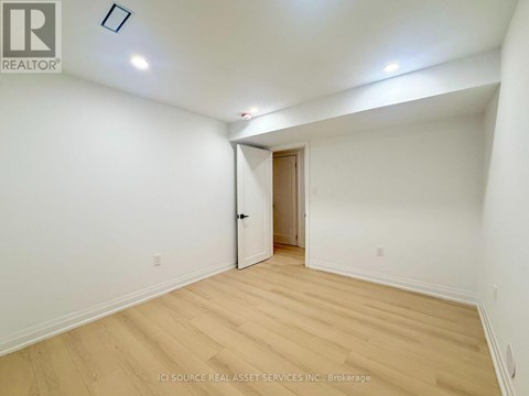 A room with a wooden floor and a door leading to another room.