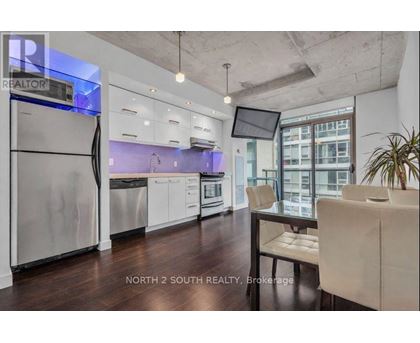 A modern kitchen with stainless steel appliances and a dining table with chairs.