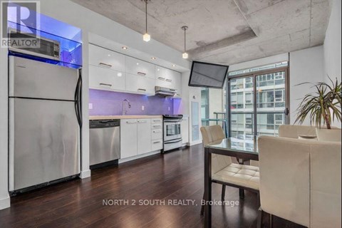 A modern kitchen with stainless steel appliances and a dining table with chairs.
