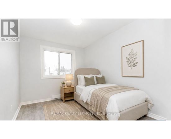 A bedroom with a bed, nightstand, and window.