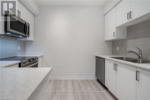 A kitchen with white cabinets and a stainless steel microwave.