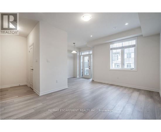 A spacious room with wooden flooring and white walls.