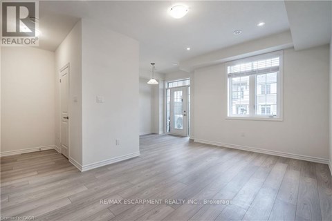 A spacious room with wooden flooring and white walls.