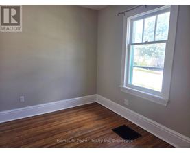 A room with a window and wooden flooring.