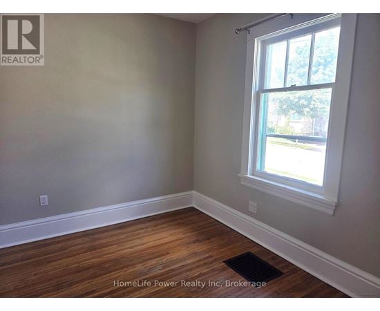 A room with a window and wooden flooring.
