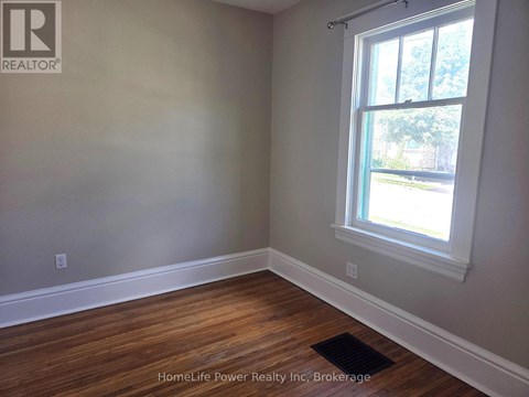 A room with a window and wooden flooring.