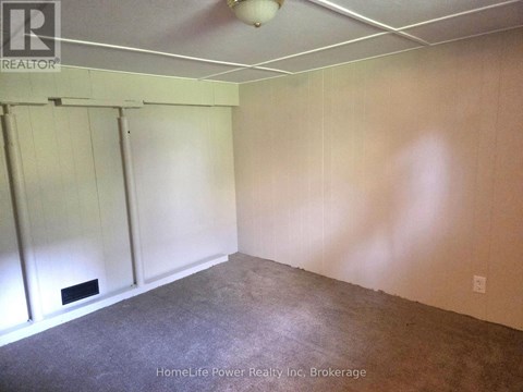A room with a carpeted floor and a white ceiling with a light fixture.