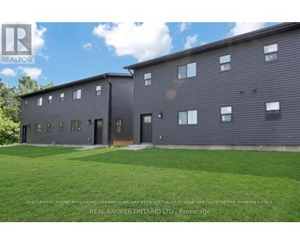 A grey building with a grassy area in front.