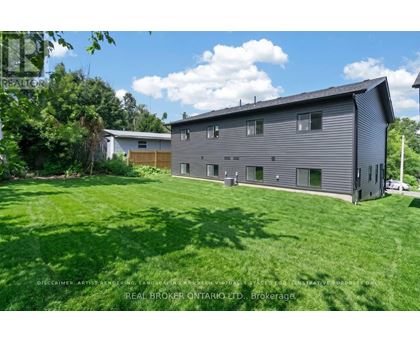 A large grey house with a white house in the background.
