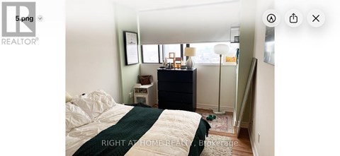A bedroom with a bed, nightstand, and a window.