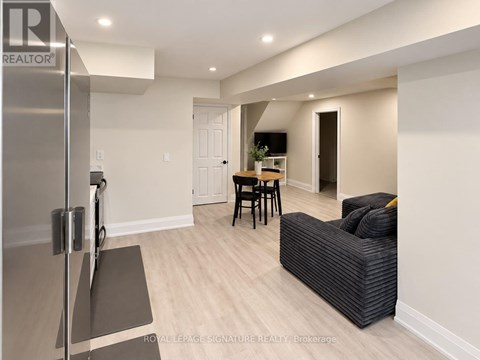 A modern kitchen with a refrigerator and a dining area with a table and chairs.