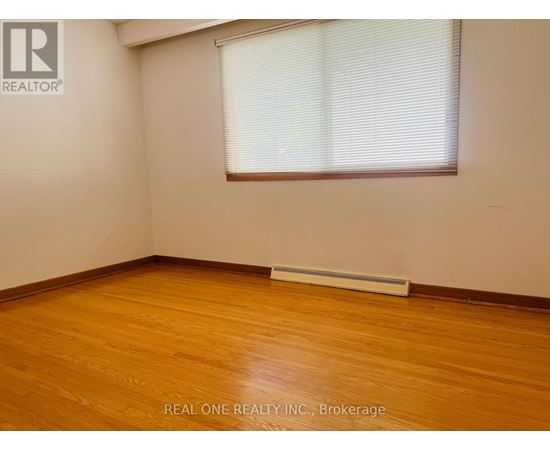 A room with wooden flooring and a window with blinds.