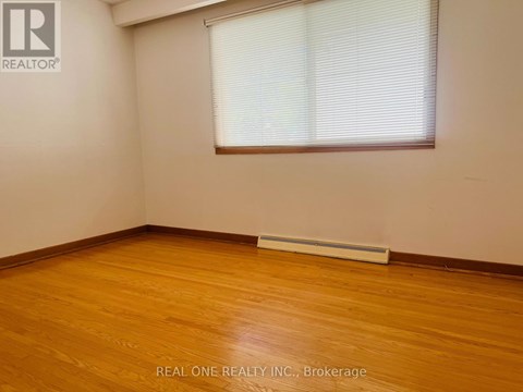 A room with wooden flooring and a window with blinds.