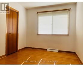 A room with a wooden floor, a door, and a window with blinds.