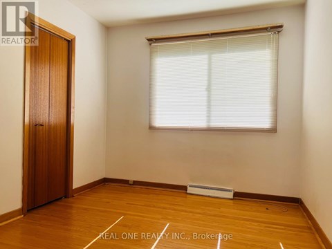 A room with a wooden floor, a door, and a window with blinds.