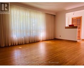 A room with wooden flooring and a large window with curtains.
