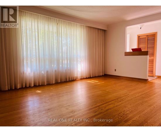 A room with wooden flooring and a large window with curtains.