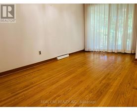 A room with wooden flooring and a window with curtains.