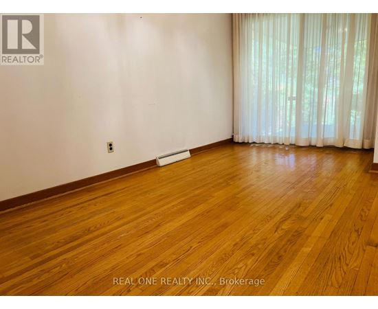 A room with wooden flooring and a window with curtains.