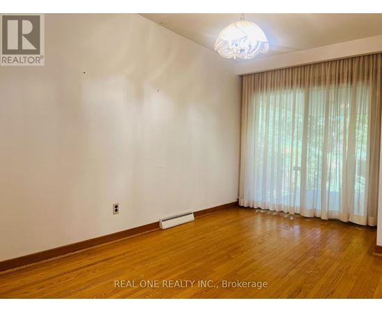 A room with wooden floors and a window with curtains.