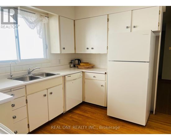 A white kitchen with wooden floors and a sink.