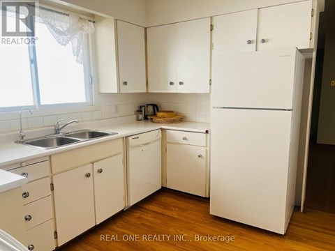 A white kitchen with wooden floors and a sink.