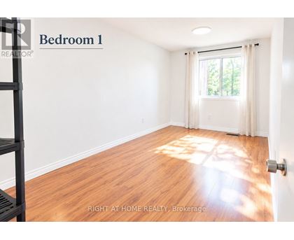 A bedroom with a window and wooden floors.