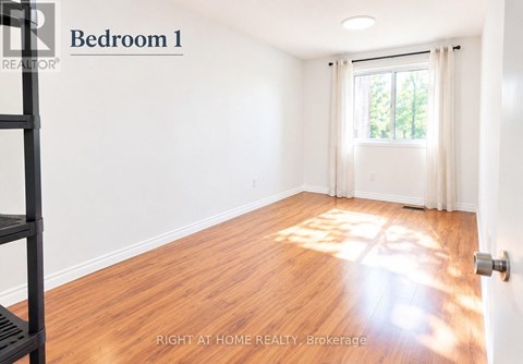 A bedroom with a window and wooden floors.
