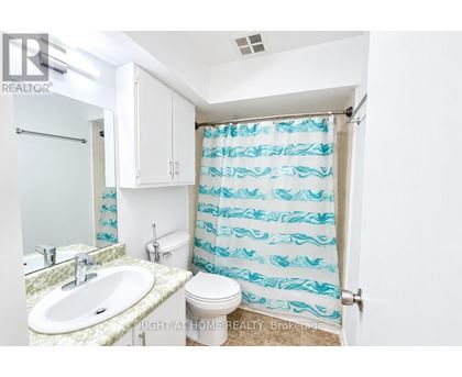 A bathroom with a sink, toilet and shower curtain.