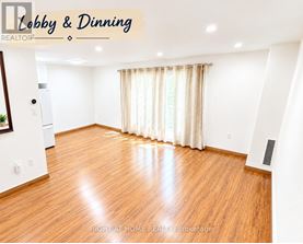 A spacious dining room with wooden flooring and white walls.