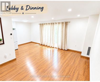 A spacious dining room with wooden flooring and white walls.