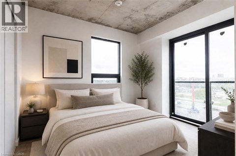 A bedroom with a large bed, a nightstand with a lamp, and a framed picture on the wall.