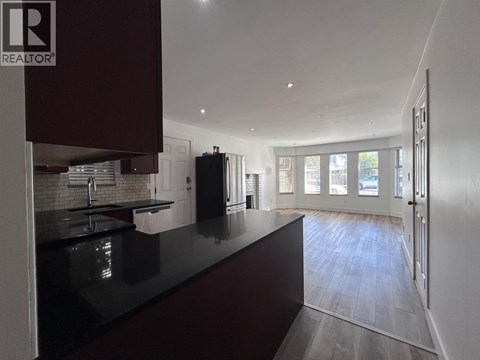 A modern kitchen with dark brown cabinets and a black countertop.