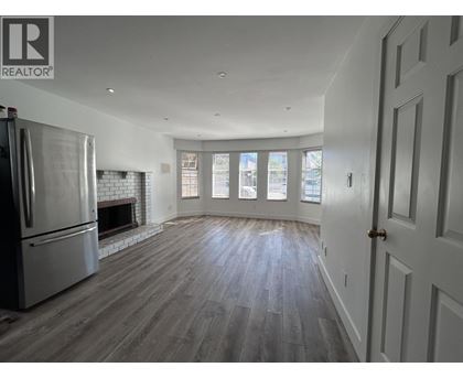 A spacious living room with wood flooring and a fireplace.