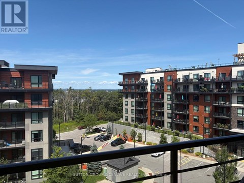A view of a residential area with apartment buildings and cars parked in the lot.