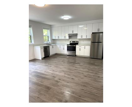 A kitchen with white cabinets and a wooden floor.
