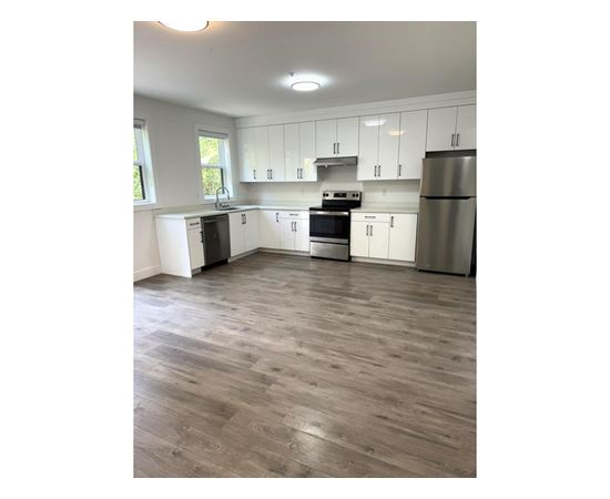 A kitchen with white cabinets and a wooden floor.