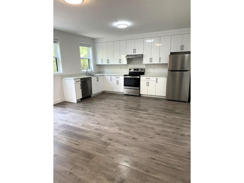 A kitchen with white cabinets and a wooden floor.