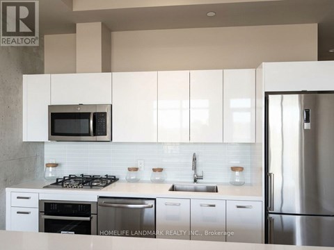 A kitchen with white cabinets and a stainless steel refrigerator.
