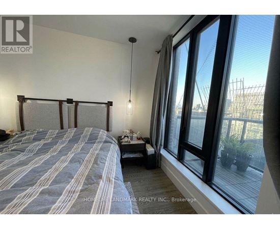 A bedroom with a large bed and a view of a construction site outside the window.