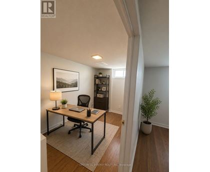 A room with a desk, chair, and a plant.