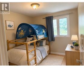 A bedroom with a bed, nightstand, and window.