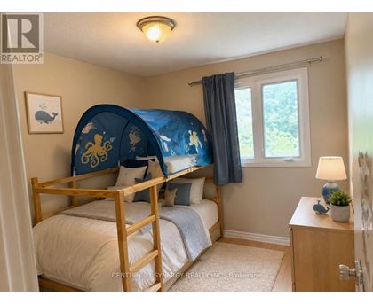 A bedroom with a bed, nightstand, and window.