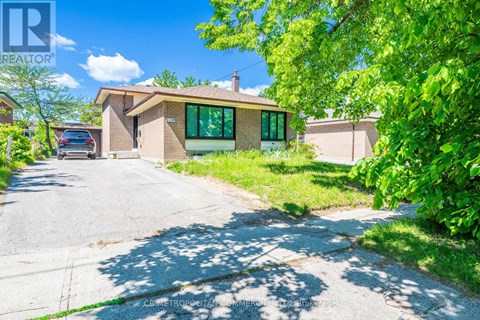 A house with a driveway in front of it surrounded by greenery.