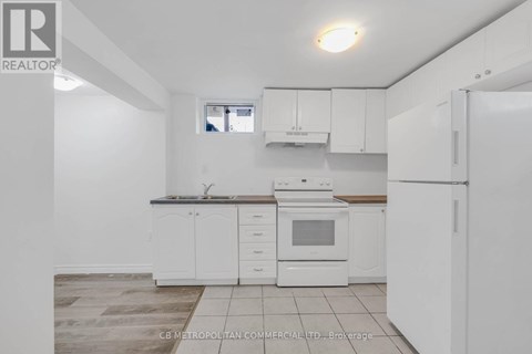 A white kitchen with a refrigerator, sink, and oven.