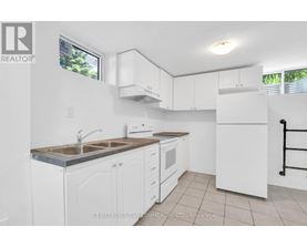 A white kitchen with a sink, stove, and refrigerator.