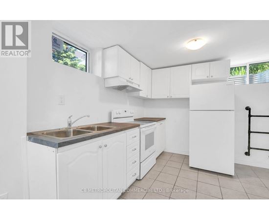A white kitchen with a sink, stove, and refrigerator.