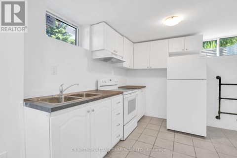 A white kitchen with a sink, stove, and refrigerator.