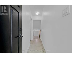 A hallway with a door on the left and a light switch on the wall.